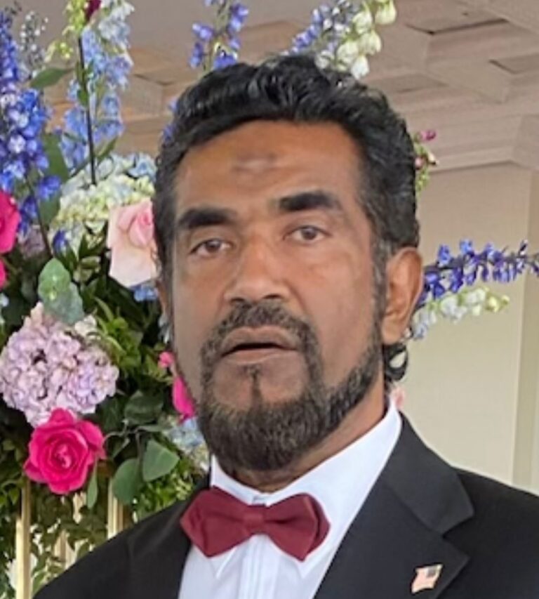 Photo of Dr. Abdoolhakim wearing a suit and white shirt and a red bowtie