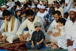 Muslims men at prayers, with their children with them